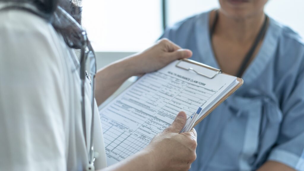 Patient health insurance claim form in doctor or nurse hands for
