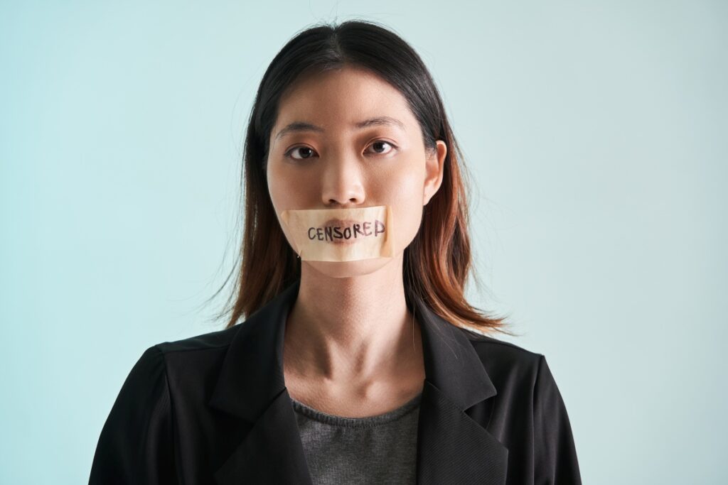 Asian woman is silenced with adhesive tape across her mouth