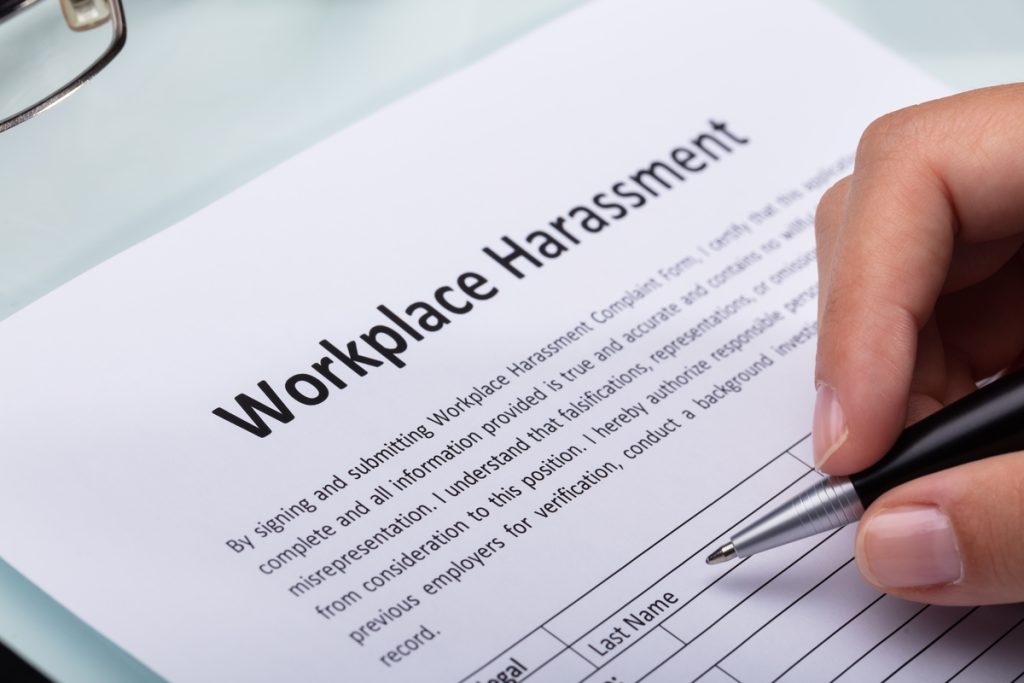 Close-up Of A Woman's Hand Filling Workplace Harassment Form